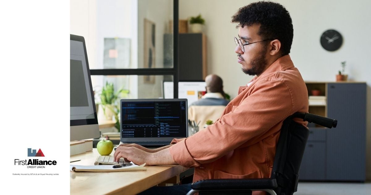 man in orange shirt sitting in a wheelchair on the computer