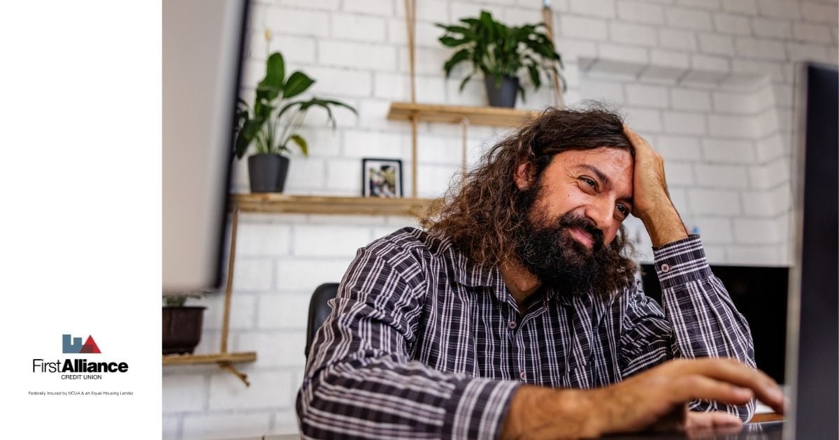 man with long brown hair looking stressed at a computer