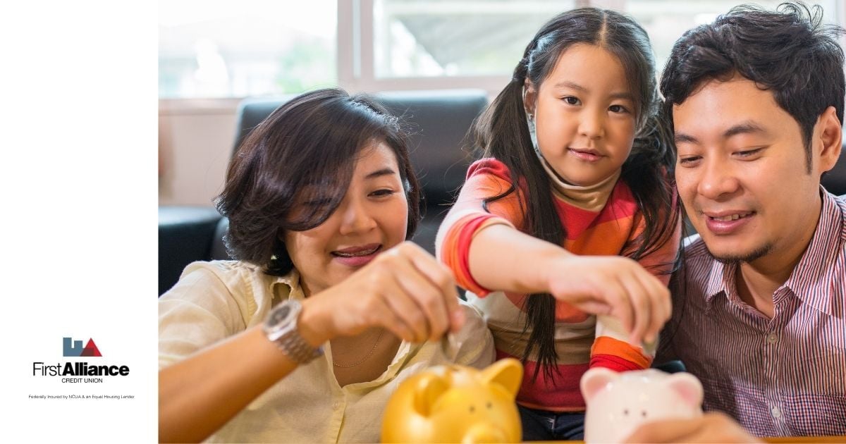 brother and sister with father putting money into piggy banks