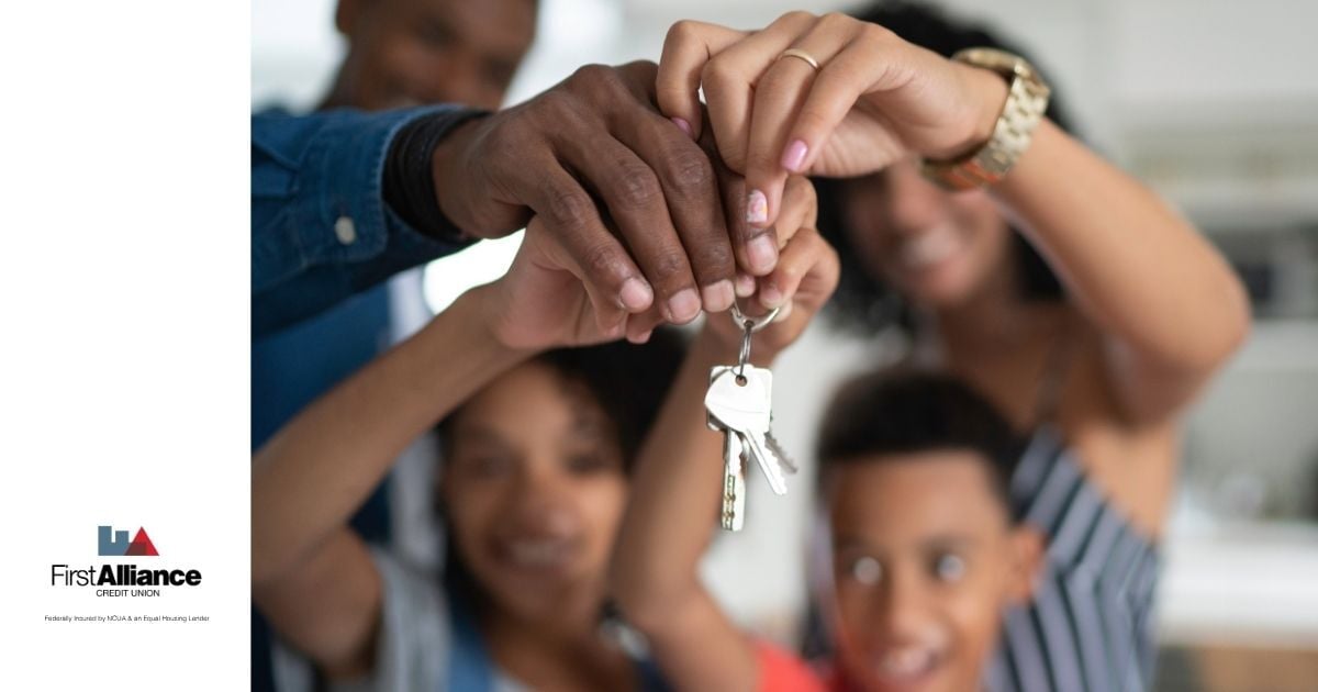 A family of four smiling and holding keys to their new home