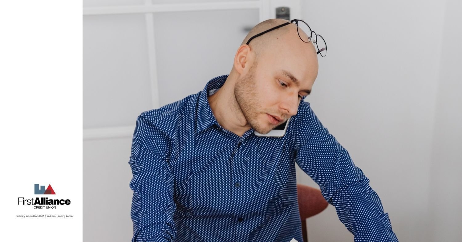 man in blue shirt on cell phone with glasses resting on his head