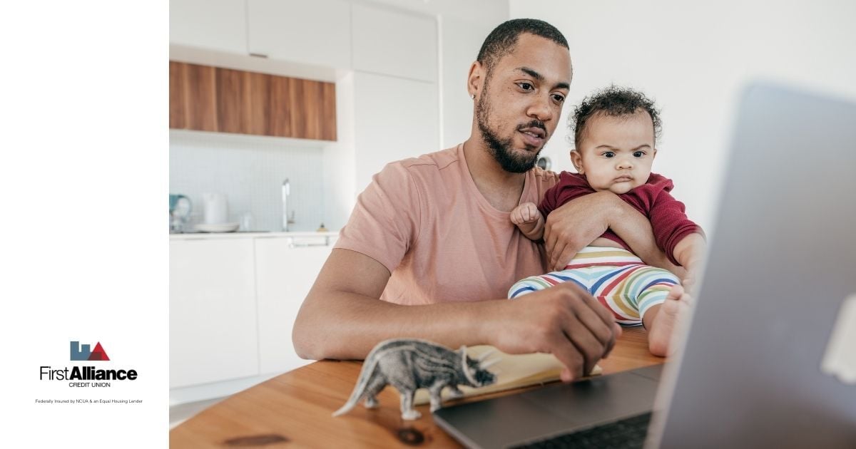 father holding young son while on computer