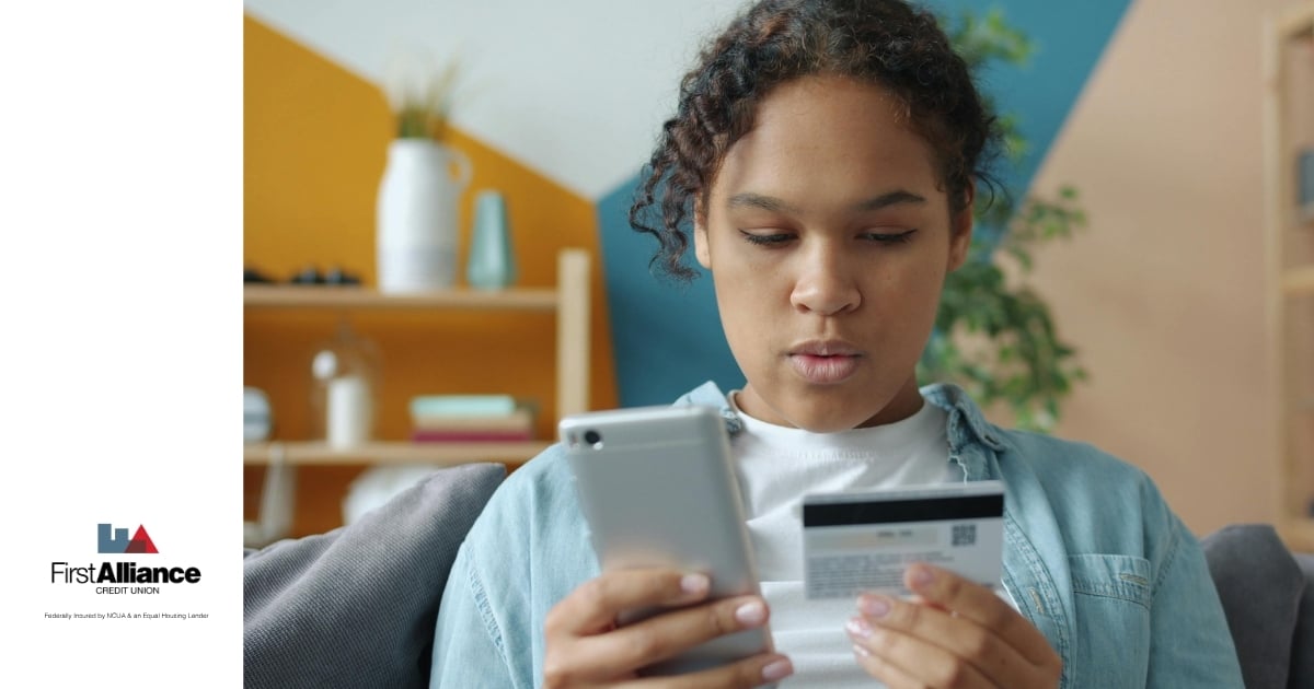 woman holding cell phone and credit card in hand