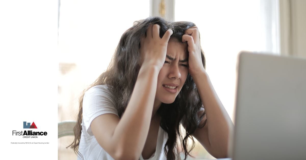woman stressed with hands in hair looking at computer