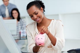 Joyful businesswoman saving money in a piggy-bank at her desk-1