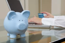 Piggy Bank on desktop as woman pays off her credit card debt | First Alliance Credit Union