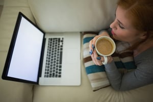 Woman on couch doing online banking on a laptop