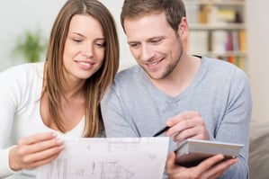  Young couple planning a new purchase together holding a calculator and the husbank pointing to a document held by the wife | First Alliance Credit Union