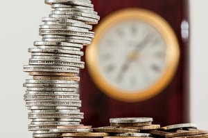 Stack of coins in front of clock