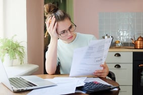 Woman with glasses at a desk looking at records | First Alliance Credit Union