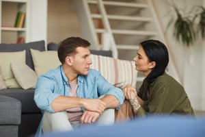 Young couple sitting in front of a sofa talking | First Alliance Credit Union