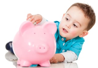 Child putting money in piggy bank