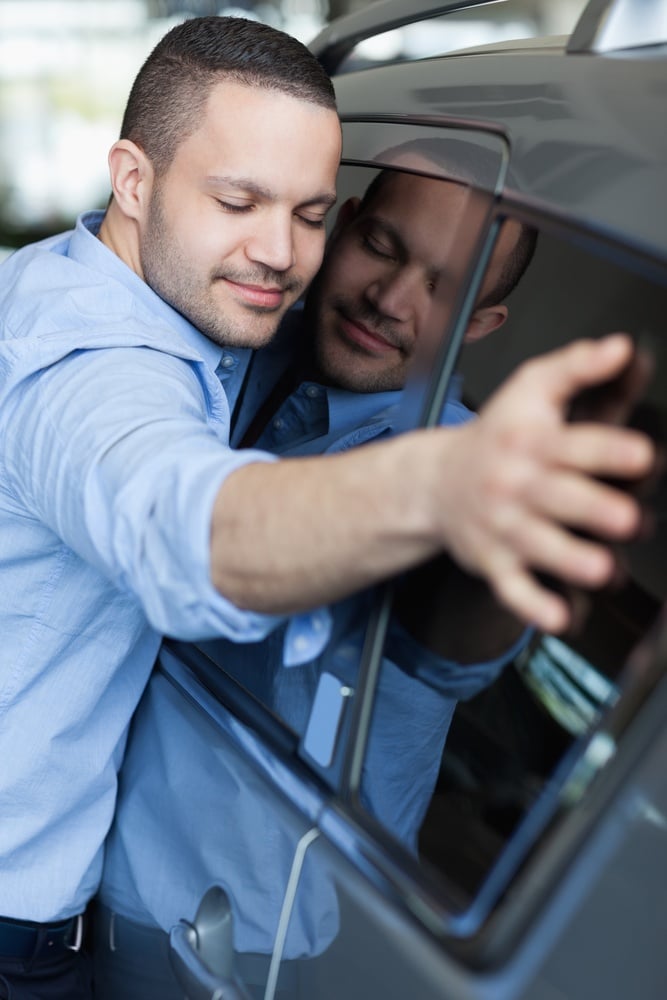 Man hugging a car in a car dealership