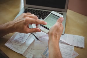 Person crunching numbers on a smartphone and laptop