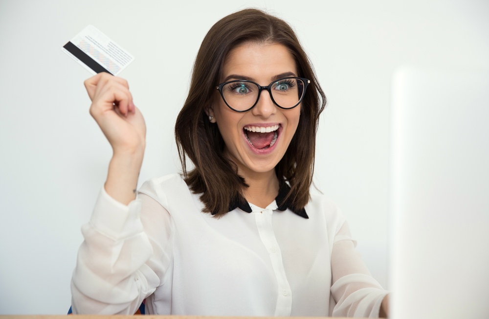 Surprised businesswoman sitting at the table with bank card