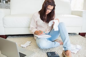 Woman sitting on floor reviewing bills