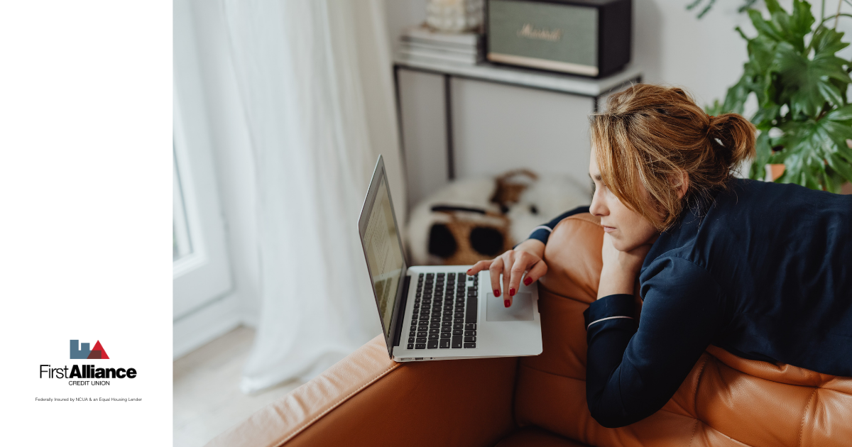 woman on laptop laying on couch looking stressed