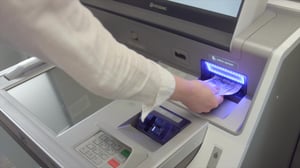 woman insert cash into kiosk to make a loan payment at first alliance credit union
