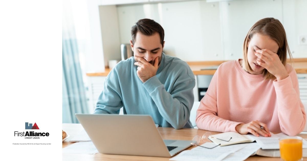 couple looking at computer and paperwork looking stressed out