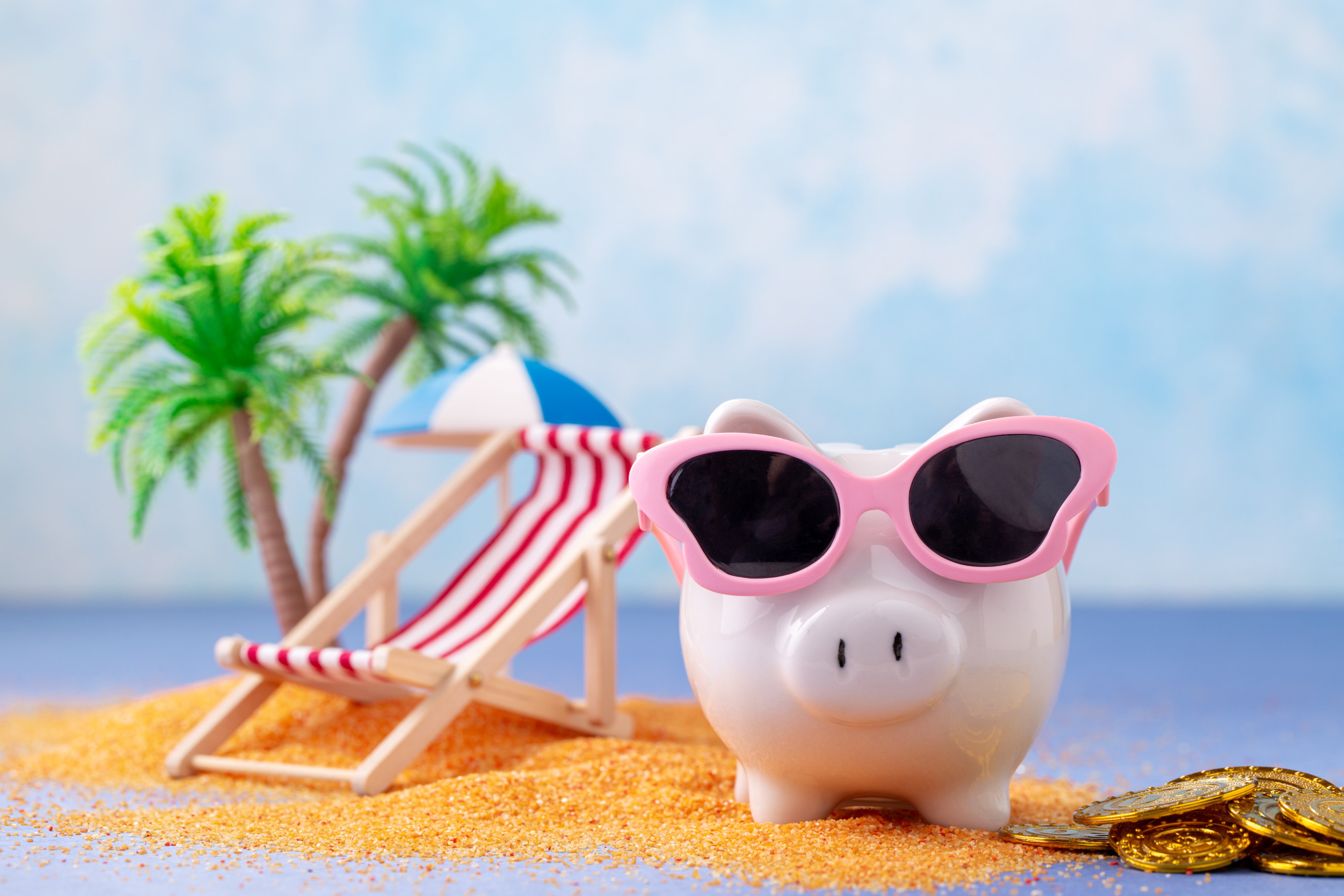 Piggy bank with sunglasses on sitting by the beach