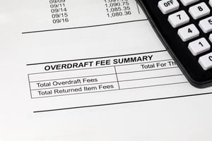 Bank statement with an overdraft fee summary with the total obscured by a calculator | First Alliance Credit Union