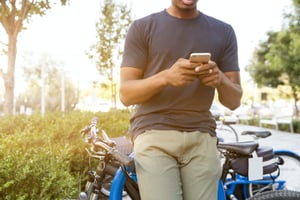 Man in front of bicycle accessing online banking on his smartphone | First Alliance Credit Union