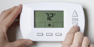 Person adjusting their thermostat