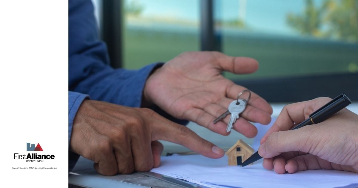 man holding a house key pointing to a small home