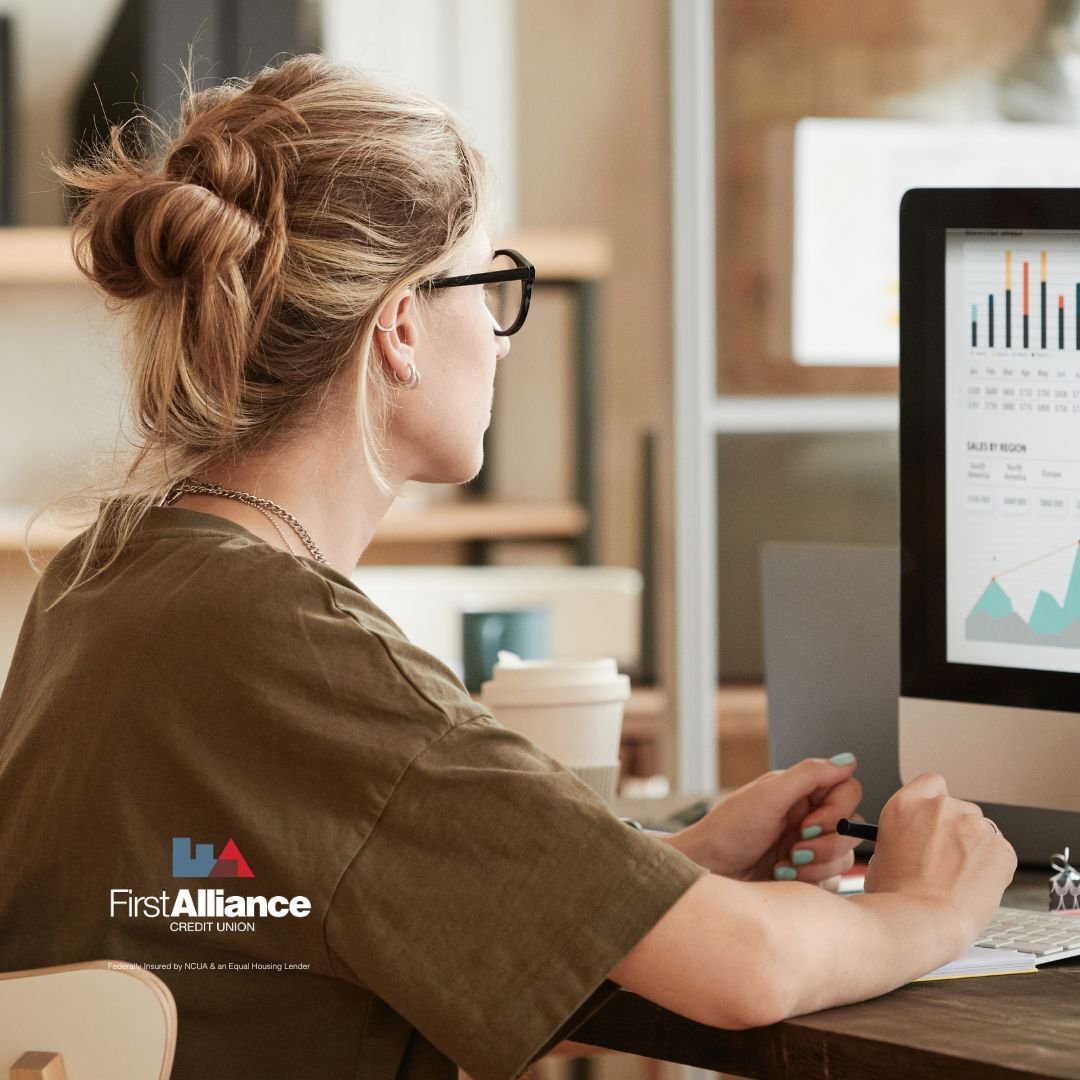 woman with blond hair in a messy bun looking at computer screen