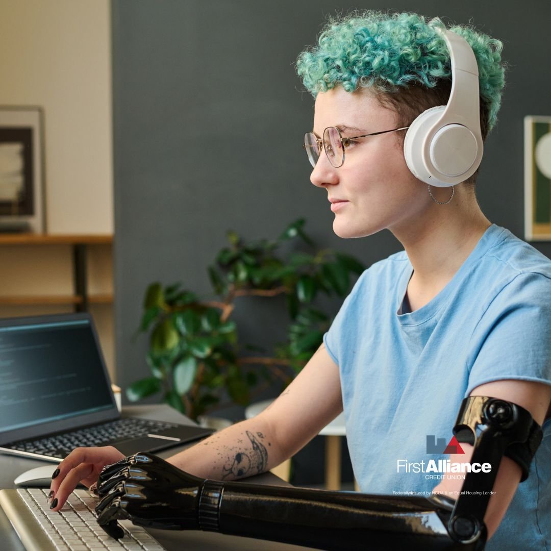 Person with prosthetic arm on computer wearing headphones